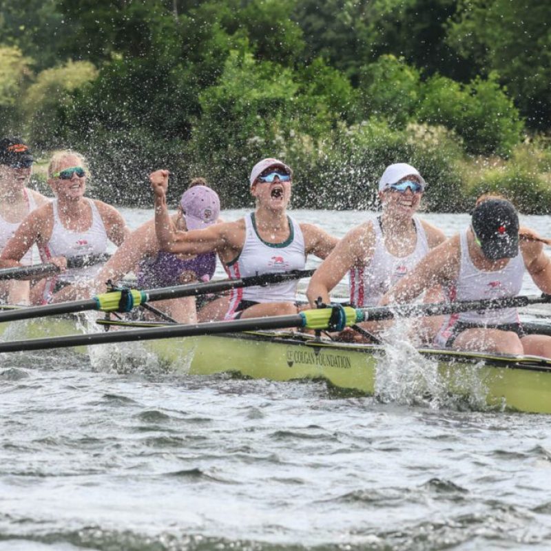 9 women in a rowing boat finishing a race